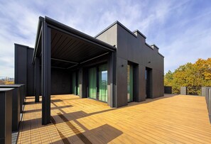A modern building with a flat roof, large windows, and a wooden deck. -  Hayashi Residence (Sofia)