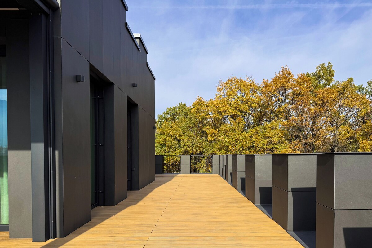 A modern building with a wooden deck leading to a glass entrance.