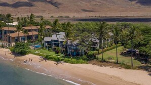 A beachfront property with multiple buildings, palm trees, and a sandy beach. - Makani A Kai A6 - On The Beach Steps To The Sand (Maalaea)