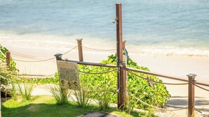 Ein Holzzaun mit einem Schild, einer Seilsperre und einem Strand im Hintergrund.