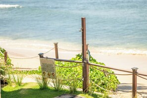 Una cerca de madera con un letrero, una barrera de cuerda y una playa al fondo.