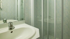 Ein Badezimmer mit Waschbecken, Spiegel und einer Duschkabine.