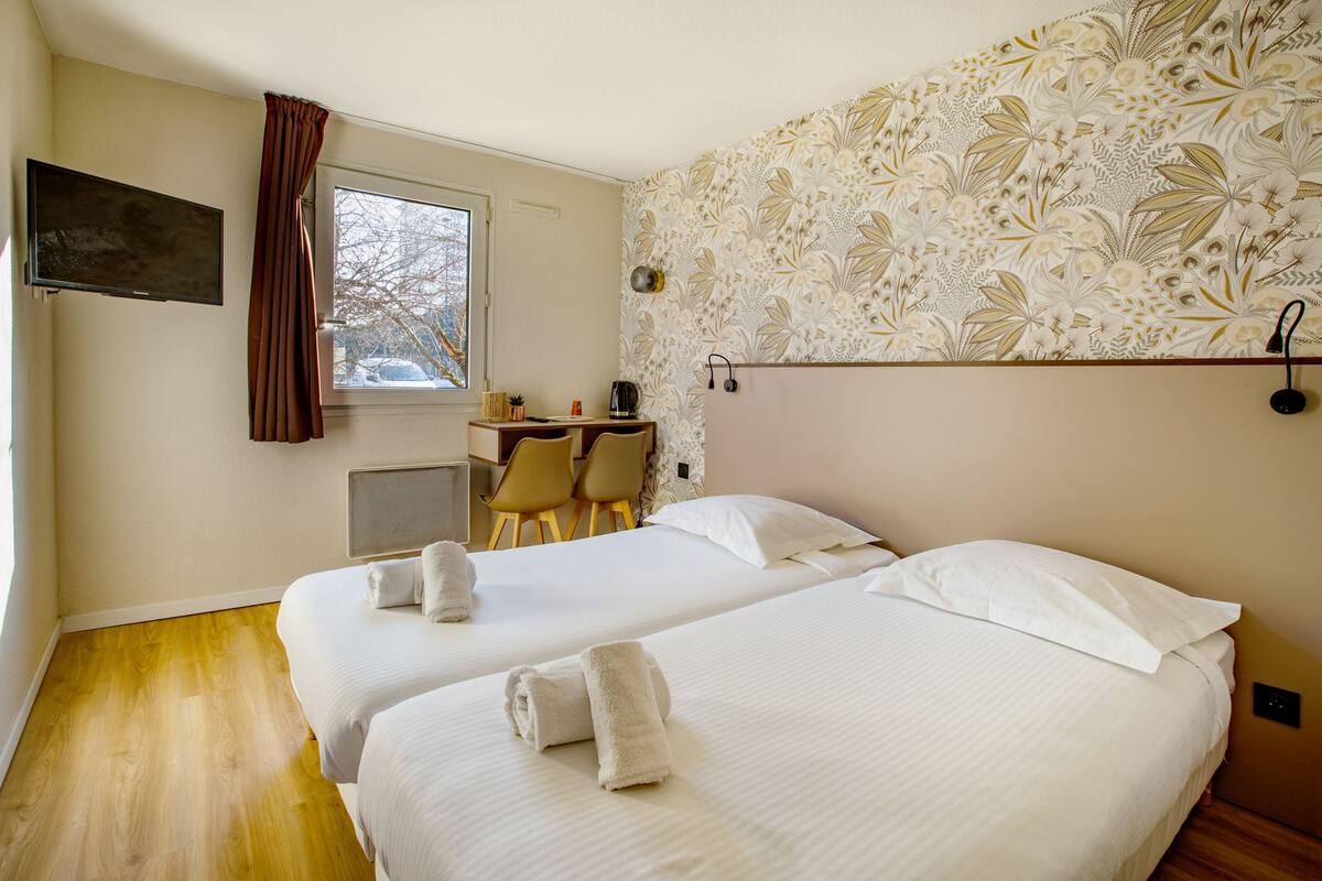 Habitación de hotel con dos camas, un escritorio y una silla.