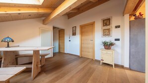 Une table à manger en bois avec des bancs, un radiateur, une porte en bois et un petit meuble sur lequel est pos ée une plante.