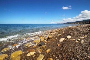 A pebble beach with clear water and distant mountains. - Relais Villa Giovanna -on the sea with garden (Marina di Caronia)