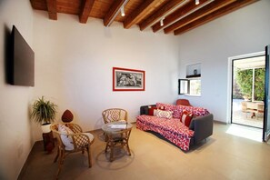 A living room with a sofa, two wicker chairs, a small table, a potted plant, and a framed picture on the wall. - Relais Villa Giovanna -on the sea with garden (Marina di Caronia)