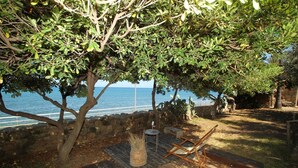 Un ponte di legno con vista sul mare, un muro in pietra e un albero che offre ombra.