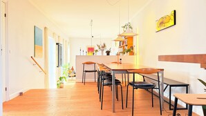 A modern dining area with a wooden table and chairs, a hanging pendant light, and a bookshelf with books and decorative items. - Great family house in CPH (Gentofte)