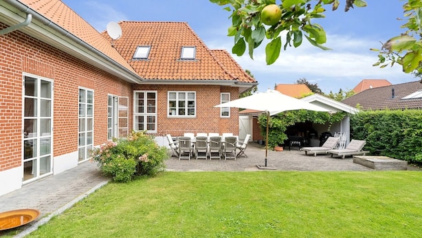 A brick house with a tiled roof, a patio with outdoor furniture, and a garden. - Great family house in CPH (Gentofte)