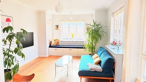 A living room with a sofa, a coffee table, a TV, and a window with a view. - Great family house in CPH (Gentofte)