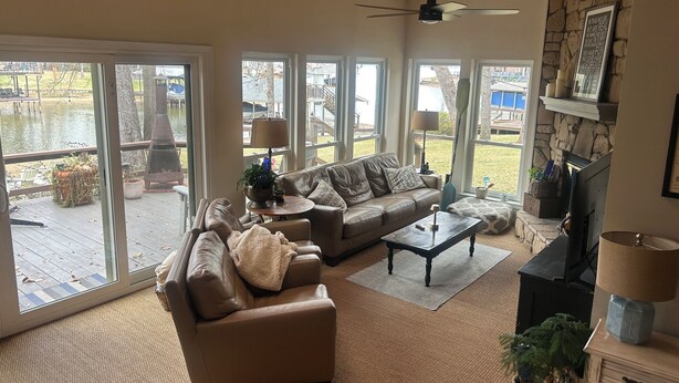 Ein geräumiges Wohnzimmer mit einer Ledersofa, einem Couchtisch und einem Kamin. Große Fenster bieten Blick ins Freie.