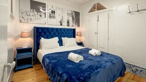 A bedroom with a large bed, two bedside tables, a wardrobe, and wall art. - Belem Historical by Homing (Lisbon)
