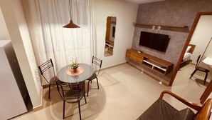 Ein modernes Wohnzimmer mit einem runden Esstisch, Stühlen, einem Fernseher und einem Sofa.