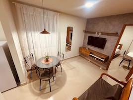 A modern living room with a round dining table, chairs, a TV, and a sofa.