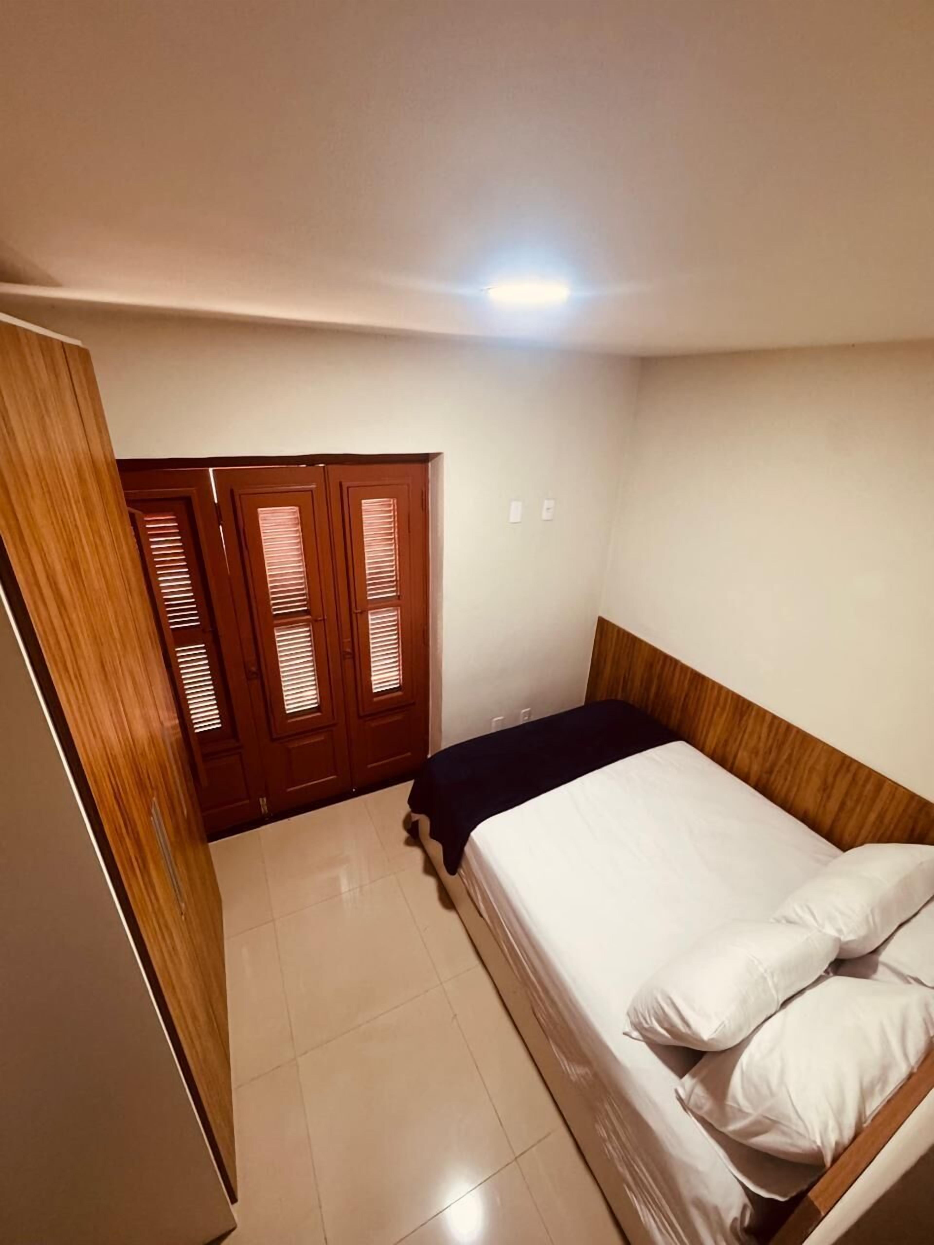 Ein Schlafzimmer mit einem Bett, einem Holzschrank und einem Fliesenboden.