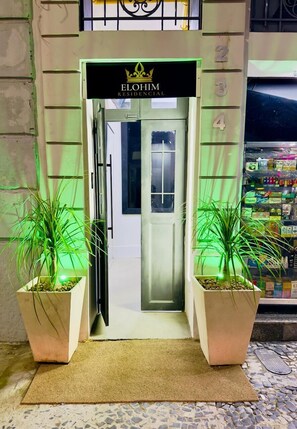 A hotel entrance with a sign reading 'ELOHIM RESIDENTIAL,' potted plants, a doormat, and a tiled floor. - Elohim Residencial (Rio de Janeiro)