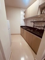 A kitchen with a black countertop, white cabinets, and a marble backsplash.