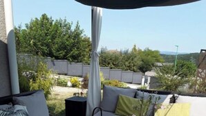 Een terras buiten met een bank, een tafel en een stoel.