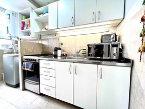 A compact kitchen with white cabinets, a microwave, a stove, and a sink. - -Belgrano- (Buenos Aires)