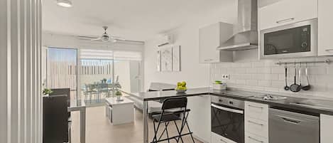 A modern kitchen with white cabinetry, a black countertop, and stainless steel appliances.