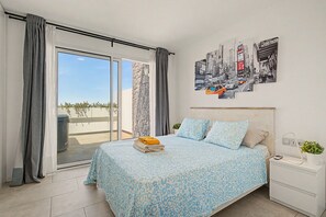 Une chambre d’hôtel avec un lit, une table de chevet, une plante en pot et une grande fenêtre avec des rideaux.