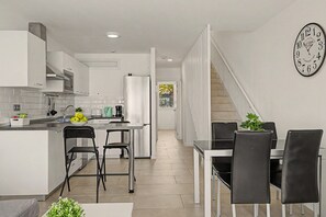 Une cuisine moderne dotée d’un îlot central, de chaises noires et d’un coin repas avec une table et des chaises.