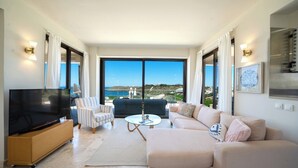 Uma sala de estar moderna com televisão de tela plana, poltrona listrada, sofá e mesa de centro de vidro.