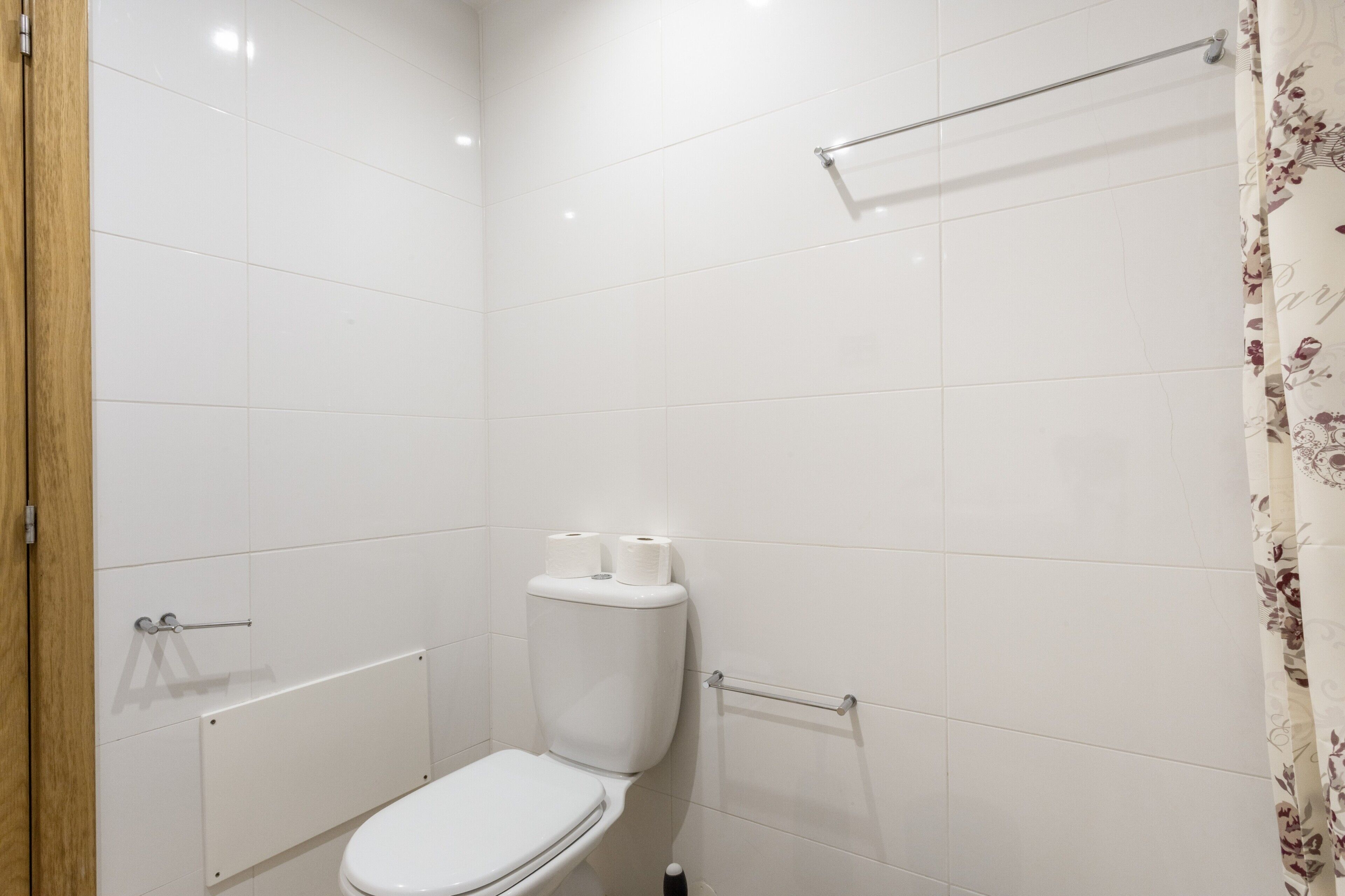 A bathroom with a toilet, a shower curtain, and a towel rack.