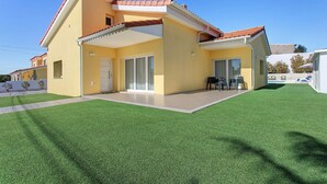 Una casa de dos pisos con techo plano, un balcón y un patio cubierto.