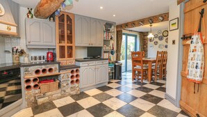 Una cocina con piso a cuadros, armarios de madera, una isla integrada con almacenamiento y un comedor con mesa y sillas de madera.