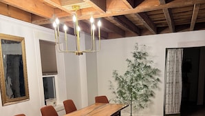 Zona de menjador amb una taula de fusta llarga, bancs i cadires vermelles.