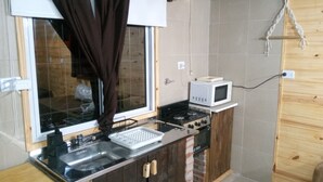 Cozinha compacta com fogão, micro-ondas, pia e armários de madeira.