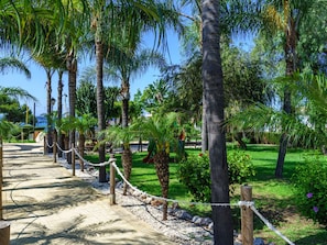A pathway lined with palm trees and a playground, surrounded by lush greenery. - Appartement-Villa, Beach Front by Interhome (Calahonda)