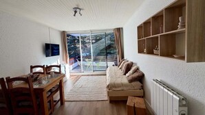 A modern living room with a wooden dining table, a sofa, and a TV mounted on the wall. - Pleasant stay in La Salle-les-Alpes for 4 people (La Salle-les-Alpes)