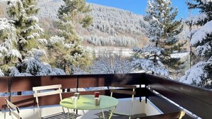 A snow-covered outdoor area with a table and chairs, surrounded by snow-laden trees and a mountain in the background. - Pleasant stay in La Salle-les-Alpes for 4 people (La Salle-les-Alpes)