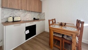 A compact kitchen with a wooden countertop, a built-in oven, and a dining area with a wooden table and chairs. - Pleasant stay in La Salle-les-Alpes for 4 people (La Salle-les-Alpes)