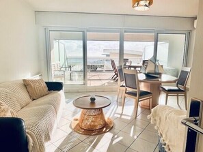A modern living room with a sofa, a round table, and chairs, large windows offering a view of the balcony and outside. - Apartment with sea and garden view in La Rochelle (La Rochelle)