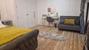 Une chambre à coucher comprenant un lit, un bureau, une chaise, un canapé et une armoire.