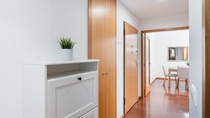 Un couloir avec une armoire blanche, une porte en bois et un coin repas comprenant une table et des chaises.