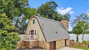 A rustic cabin with a stone chimney, a wooden deck, and a small porch. - 3-bedroom waterfront cottage with unmatched views and dock on Tennessee River (Decatur)