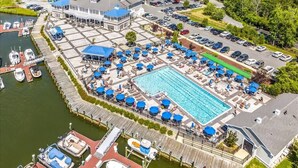 Oversigtsbillede af en ejendom ved vandet med swimmingpool, fortøjede både og parkeringsplads.