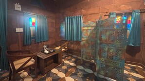 Een kamer met een kamer met een vloer met een patroon, houten meubels en een decoratief scherm.