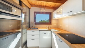 Una cocina moderna con vigas de madera en el techo, lavavajillas y ventana con vistas.