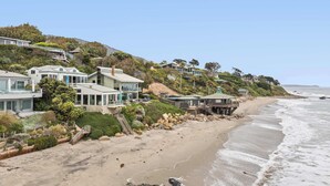 A coastal residential area with modern houses, a beach, and a rocky shoreline.