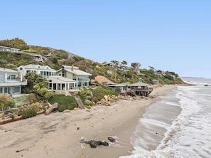 Una zona residencial costera con casas modernas, una playa y un litoral rocoso.