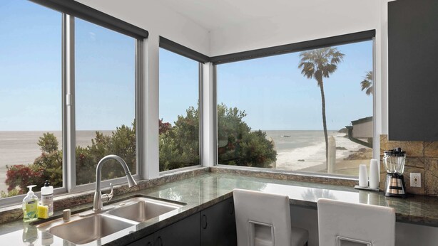 A kitchen with large windows, a sink, and a blender on the counter.