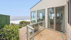 A modern building with large glass windows, a patio area, and a view of the ocean.