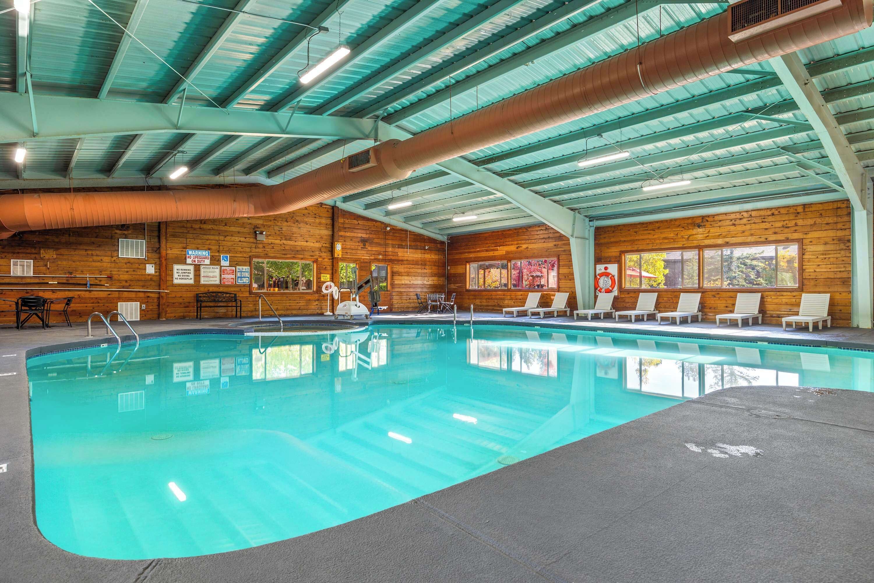 Ein Hallenbad mit klarem Wasser, Holzwänden und einer hohen Decke mit freiliegenden Lüftungsrohren.