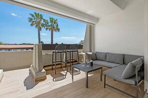 Un balcon avec un canapé, deux chaises, une table et une bouteille de vin.