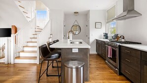 Una cucina moderna con isola centrale, elettrodomestici in acciaio inossidabile e una scala in legno.